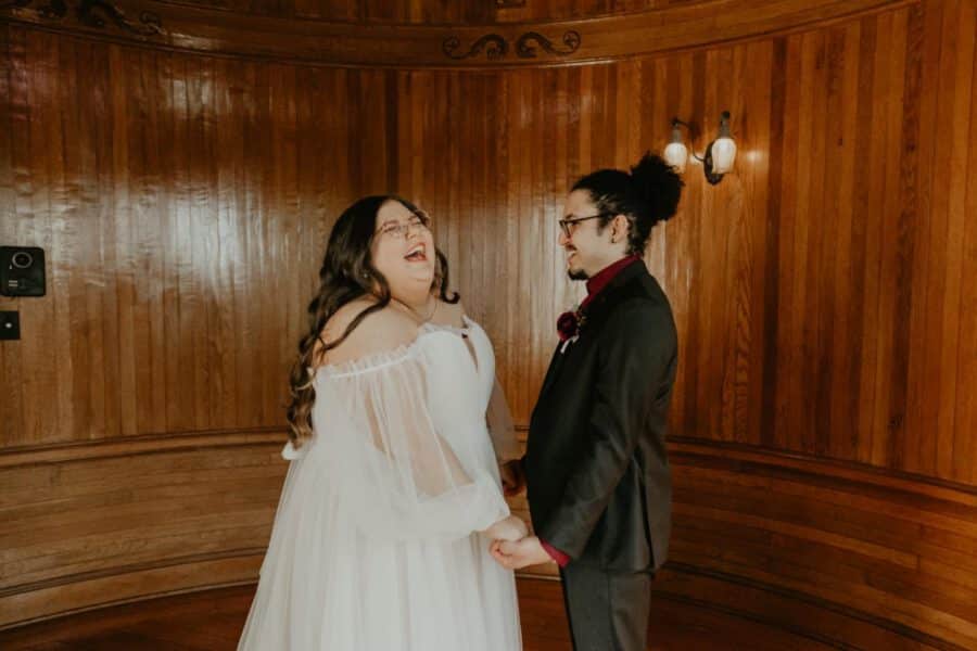 plus-size wedding gown with sheer off-the-shoulder sleeves and a flowing tulle skirt, perfect for a timeless and elegant outdoor ceremony.