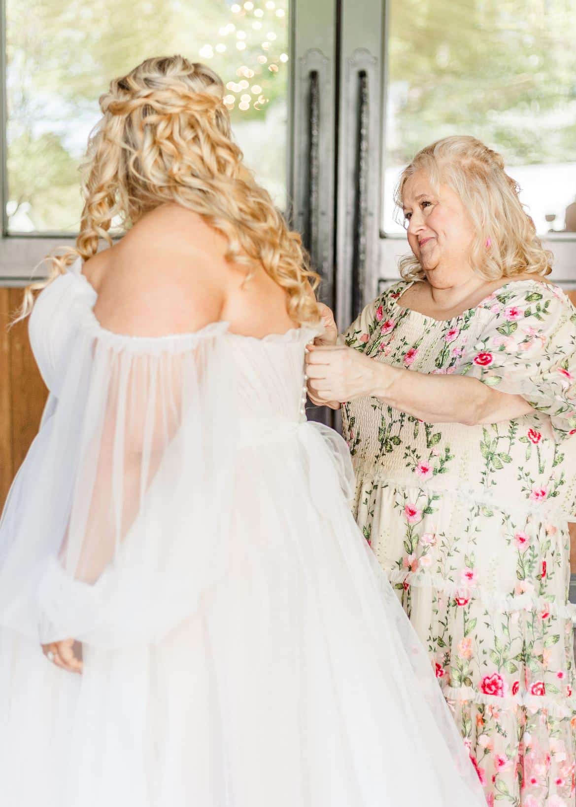Romantic plus-size bridal gown featuring off-the-shoulder sheer sleeves, a flowing tulle skirt, and a dramatic cathedral-length veil, perfect for an ethereal and timeless wedding look.