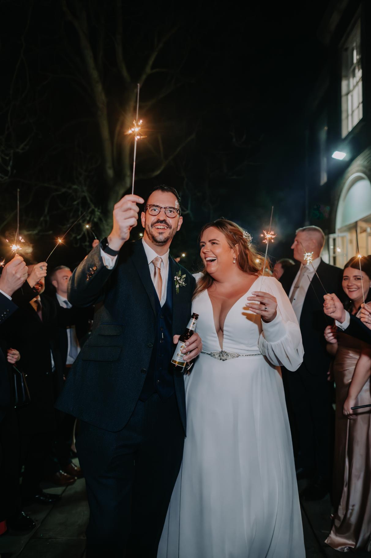 plus-size wedding gown featuring long sleeves, a plunging V-neckline, and a cinched waist with a jeweled belt, perfect for a timeless and sophisticated bridal look