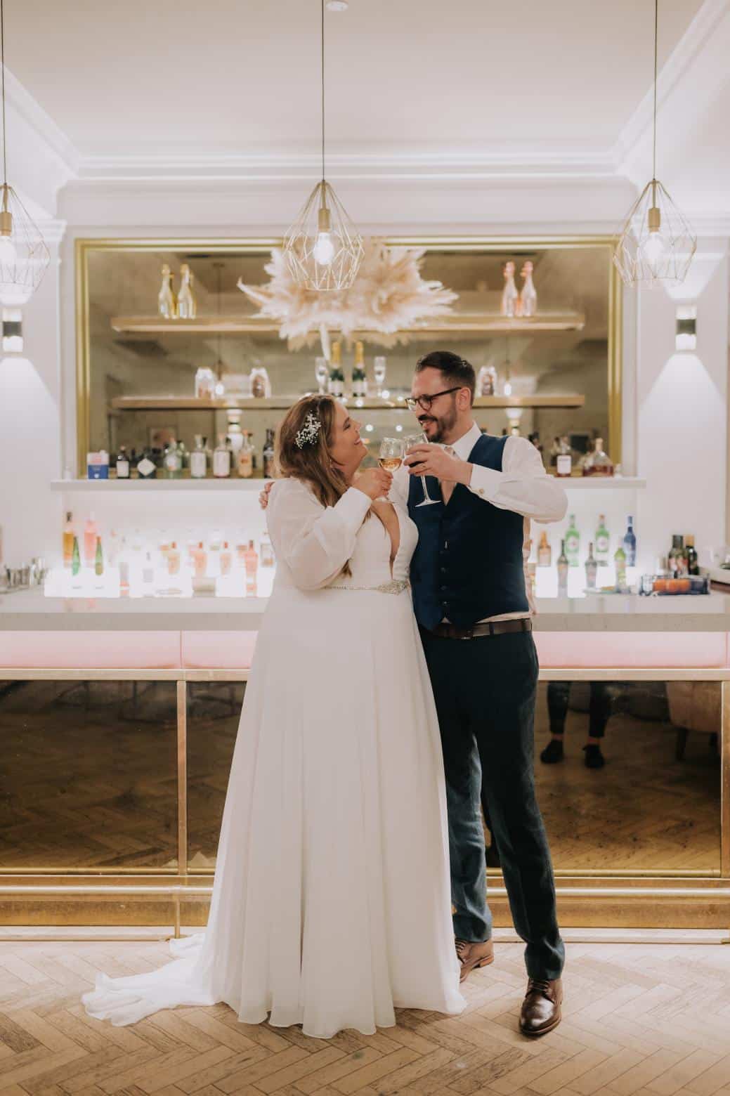 plus-size wedding gown featuring long sleeves, a plunging V-neckline, and a cinched waist with a jeweled belt, perfect for a timeless and sophisticated bridal look