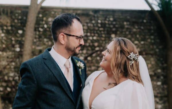 plus-size wedding gown featuring long sleeves, a plunging V-neckline, and a cinched waist with a jeweled belt, perfect for a timeless and sophisticated bridal look