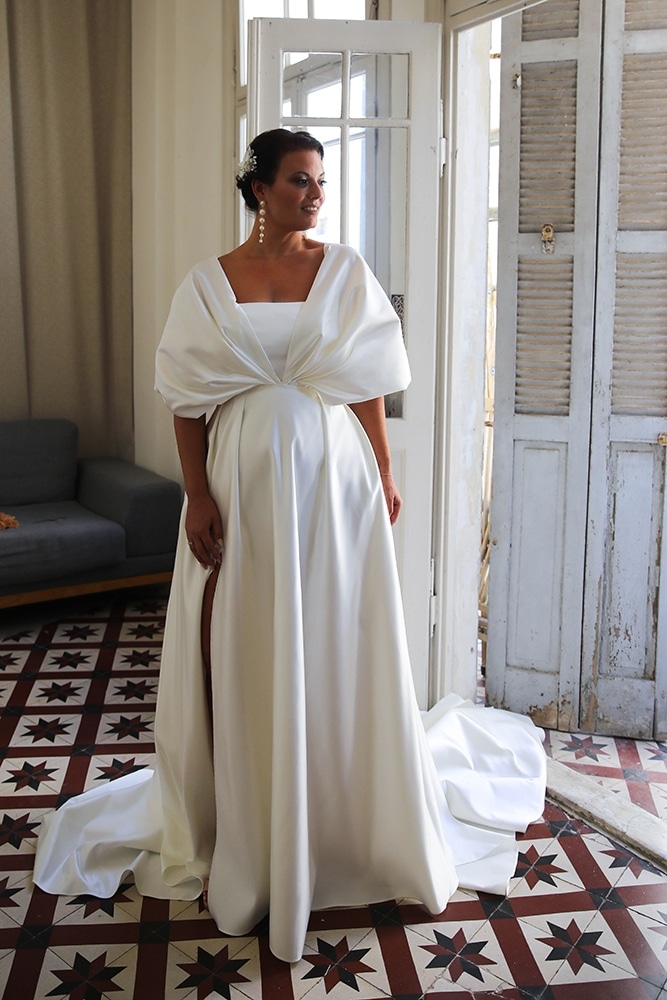 Elegant plus-size bride wearing a statement wedding gown with a dramatic oversized bow detail. The sophisticated design and soft draping create a regal and unforgettable bridal look