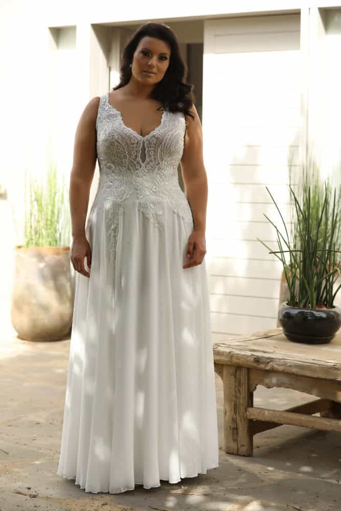 The plus-size bride, dressed in a romantic sleeveless lace gown adorned with delicate floral patterns