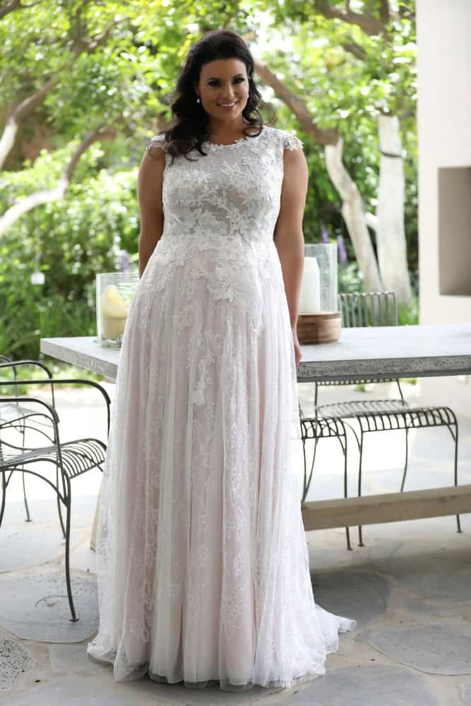 The plus-size bride, dressed in a romantic sleeveless lace gown adorned with delicate floral patterns