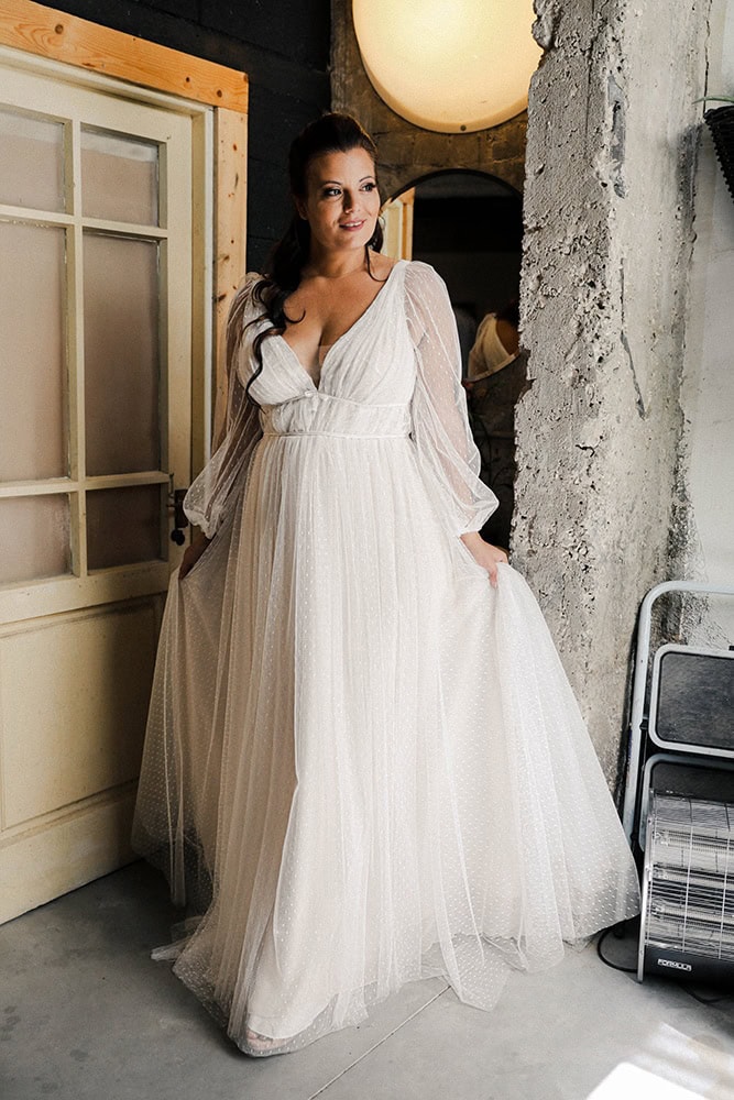 A plus-size bride in a plunging neckline dotted tulle wedding dress with sheer bishop sleeves,