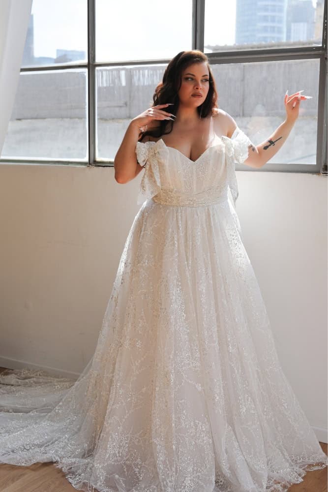 Plus-size bride in a glittering ball gown with off-the-shoulder straps and a sweetheart neckline