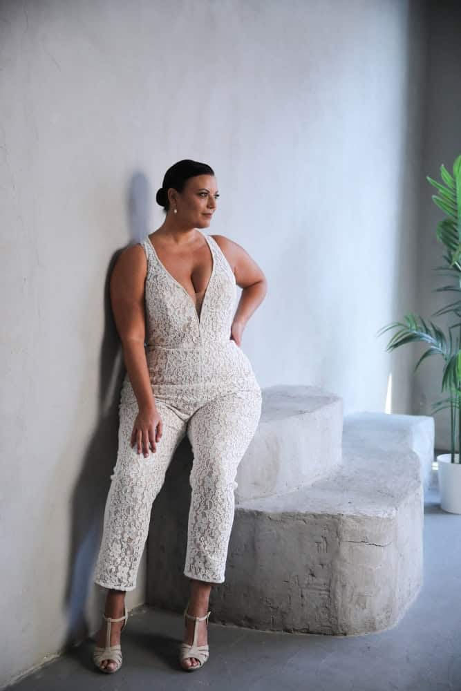 Plus-size bride in a lace bridal jumpsuit with a deep V-neckline and fitted silhouette