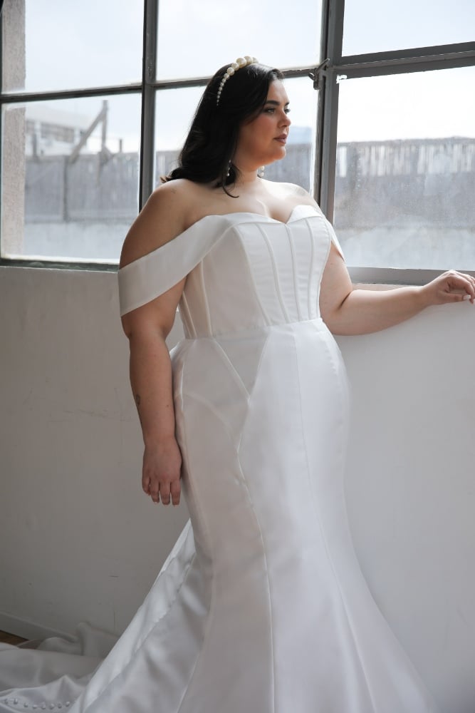 Plus-size bride in an off-the-shoulder satin mermaid wedding gown with a corset bodice