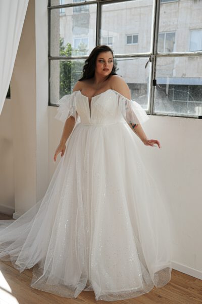 Plus-size bride in a glittering ball gown with off-the-shoulder ruffled sleeves and a sweetheart neckline