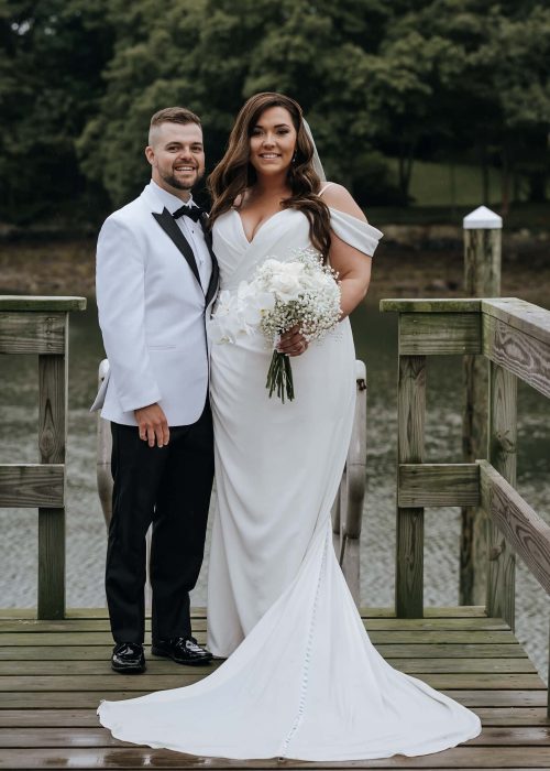 Bride and groom smiling on wooden dock by lake